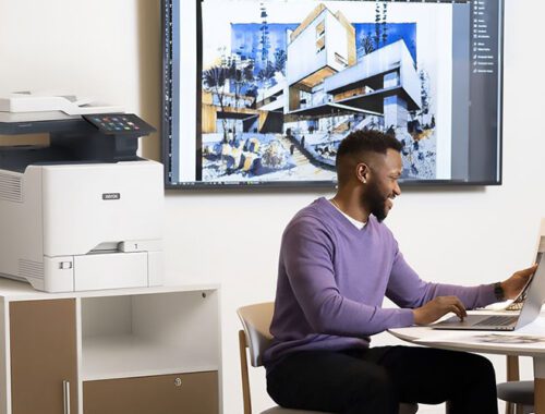 Men working on a laptop in front of a Xerox® VersaLink® C415 Colour Multifunction Printer