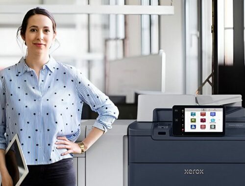 A woman standing beside the Xerox® PrimeLink® C9200 Series Printer in a modern office environment